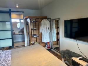 a room with a tv and a room with a dress rack at B&B Tussen Vecht en Veer in Hardenberg