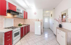 a kitchen with red cabinets and a white refrigerator at Cozy Apartment In Vodnjan With Wifi in Vodnjan