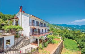 una casa en una colina con balcones y árboles en Cozy Apartment In Lovran With Kitchen, en Lovran