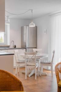 cocina blanca con mesa blanca y sillas en Renoviertes Apartment mit Terrasse an der Piste mit kostenlosen WiFi, en Carezza al Lago