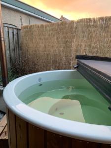 a bath tub filled with green water next to a fence at Tiny House Thuus in Sint Annaland