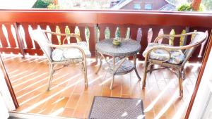 un porche con 3 sillas, una mesa y un taburete en Ferienwohnung Vogelsang, en Undeloh