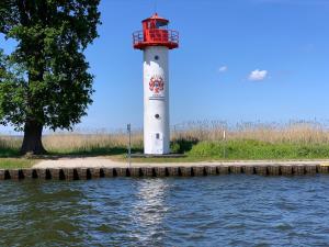 a red and white lighthouse next to a body of water at Ferienwohnung Alois in Ueckermünde