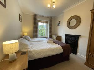a bedroom with a large bed and a fireplace at Tawny Cottage in Portinscale
