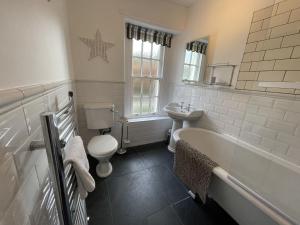a bathroom with a toilet a sink and a bath tub at Tawny Cottage in Portinscale +22 photos