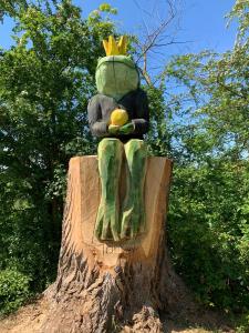 a statue of a frog sitting on a tree stump at Ferienwohnung Alois in Ueckermünde