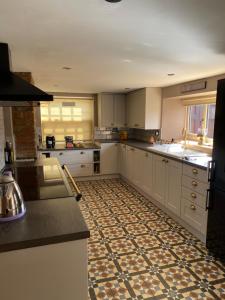 uma grande cozinha com armários brancos e piso em azulejo em Ivy House, three bed cottage, parking garden em Skipsea