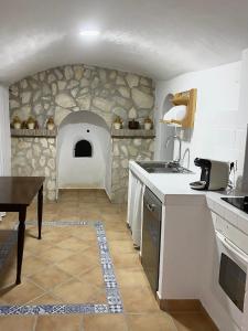 a kitchen with a stone wall with a oven at Cueva de Ramón y Elvira in Cuevas del Campo