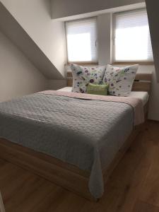 a bedroom with a bed with pillows and two windows at Ferienwohnung Alois in Ueckermünde