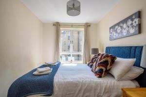 a bedroom with a bed with a blue chair and a window at Charming & Spacious 3BR With Private Parking Near Ipswich in Ipswich