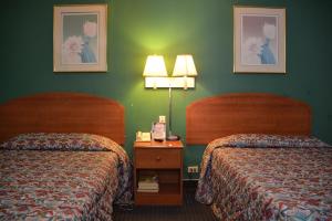 twee bedden in een hotelkamer met groene muren bij Stay Express Inn Near Ft. Sam Houston in San Antonio