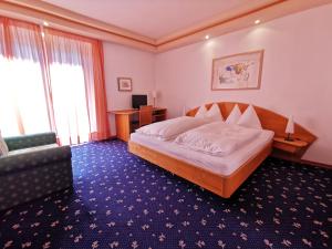 a bedroom with a bed and a desk and a couch at Hotel Burgleitenhof in Lana