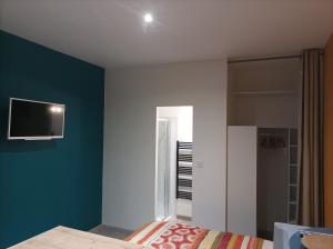 ein Schlafzimmer mit einer blauen Wand und einem TV an der Wand in der Unterkunft Bienvenue chez Seamora et Maelia in Saint Etienne