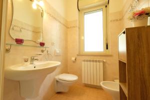 een badkamer met een wastafel, een toilet en een spiegel bij Armonia Pineto Vacanza in Pineto