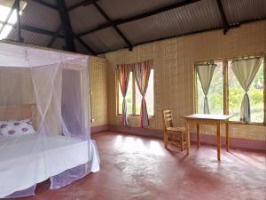 a bedroom with a bed and a table and windows at Nguse River Camp in Kikube