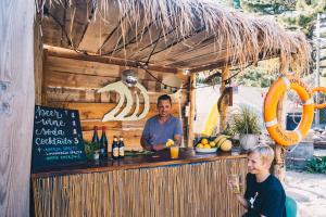 Ein Mann, der in einer Bar sitzt und hinter ihm steht. in der Unterkunft Surfana Beach Bed & Breakfast Bloemendaal in Overveen