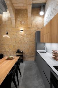 cocina con mesa de madera y pared de piedra en NUMRU 27 Expertly restored small house of character, en Cospicua