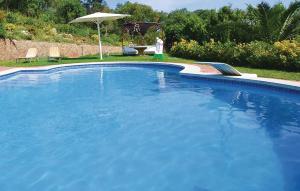 a woman standing next to a large blue swimming pool at Cozy Home In Palafolls in Mas Carbo