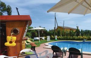 a pool with chairs and an umbrella next to a house at Cozy Home In Palafolls in Mas Carbo