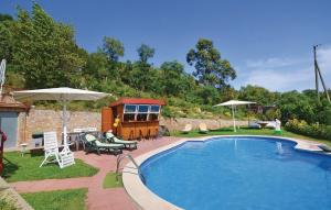a swimming pool with chairs and umbrellas in a yard at Cozy Home In Palafolls in Mas Carbo