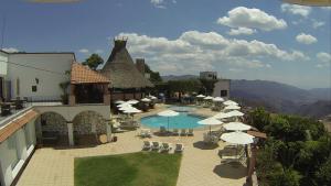 a resort with a pool and tables and chairs and umbrellas at Hotel Montetaxco in Taxco de Alarcón