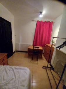 ein Wohnzimmer mit einem roten Vorhang und einem Schreibtisch in der Unterkunft Alistair lodge in Chatham