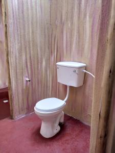 um WC branco num quarto com uma parede de madeira em Nguse River Camp em Kikube