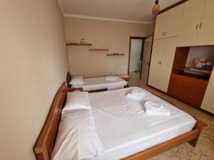 1 dormitorio con 2 camas con sábanas blancas en Apartament Orion, en Vlorë
