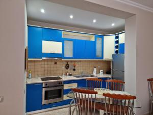une cuisine avec des armoires bleues, une table et des chaises dans l'établissement Apartament Orion, à Vlorë
