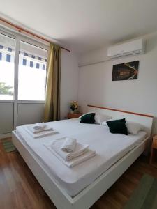 a bedroom with a large white bed with towels on it at Apartments Grebović in Dubrovnik