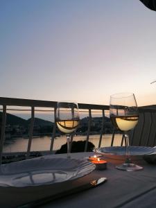 dos copas de vino sentadas en una mesa con la puesta de sol en Apartments Grebović, en Dubrovnik