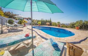 ein Swimmingpool mit zwei Stühlen und einem Sonnenschirm in der Unterkunft Beautiful Home In Frigiliana in Frigiliana + 13 Fotos