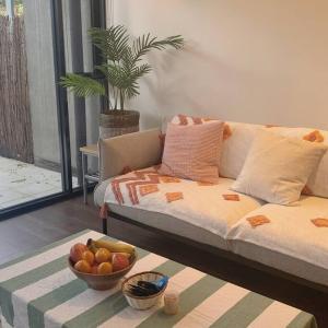 a living room with a couch and a bowl of fruit at Light-filled apartment in a dream location 150m away from University of Melbourne in Melbourne