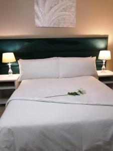 a large white bed with two lamps and flowers on it at Cascades Self-Catering Apartments in Summerstrand