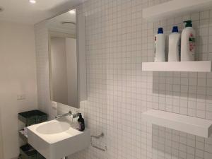 a white tiled bathroom with a sink and a mirror at Light-filled apartment in a dream location 150m away from University of Melbourne in Melbourne