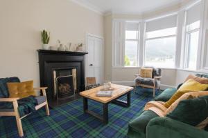 a living room with a fireplace and a couch and a table at Rossmay House - 4 Bedroom Scottish Villa with waterfront / mountain views in Arrochar