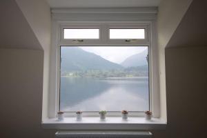 a window in a room with a view of the water at Rossmay House - 4 Bedroom Scottish Villa with waterfront / mountain views in Arrochar