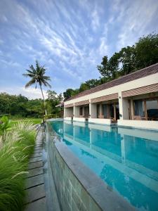 a swimming pool in front of a building with a palm tree at boutique villa jogja senang in Yogyakarta