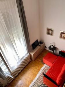 ブダペストにあるV. District Apartmentのリビングルーム(赤いソファ、大きな窓付)