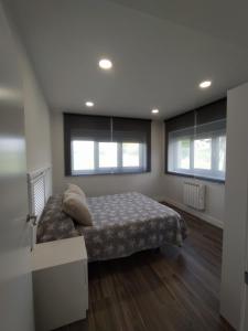 een slaapkamer met een bed en 2 ramen bij Apartamento Manuela, totalmente nuevo, 8 km de la playa in Llanes