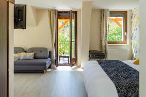 Un dormitorio con una cama y un sofá y ventanas. en Logis Hotel Des Vosges, en Sewen