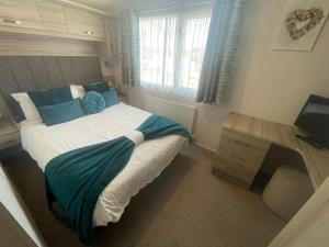 a bedroom with a bed and a table and a window at Lakeside Retreat 3 with hot tub, private fishing peg situated at Tattershall Lakes Country Park in Tattershall