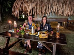 un hombre y una mujer sentados en una mesa con copas de vino en Yala Lake View Cabanas en Tissamaharama