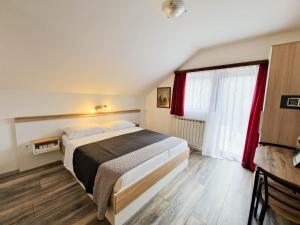 a bedroom with a bed and a window with red curtains at Rooms Ruza in Smoljanac