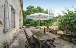einen Holztisch und Stühle mit Sonnenschirm in der Unterkunft Beautiful Home In St Germain With Kitchen in Saint-Germain-de-la-Rivière