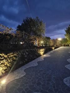 - une piscine avec un mur en pierre la nuit dans l'établissement Turismo Rurale Filieri, à Dorgali