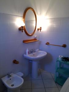 a bathroom with a sink and a mirror and a toilet at Casa GiovanMarco con vista mare in Santa Teresa Gallura