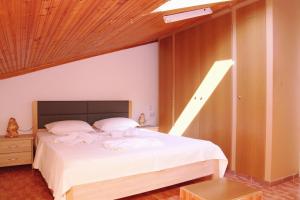 a bedroom with a white bed with a wooden ceiling at Ourania luxury apartment in Keramotí