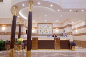 a man standing at the counter of a hotel lobby at Sukoon Hotel in Al Madinah
