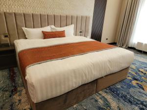 ein großes Bett in einem Hotelzimmer mit einem großen Fenster in der Unterkunft New West Hotel in Ulaanbaatar